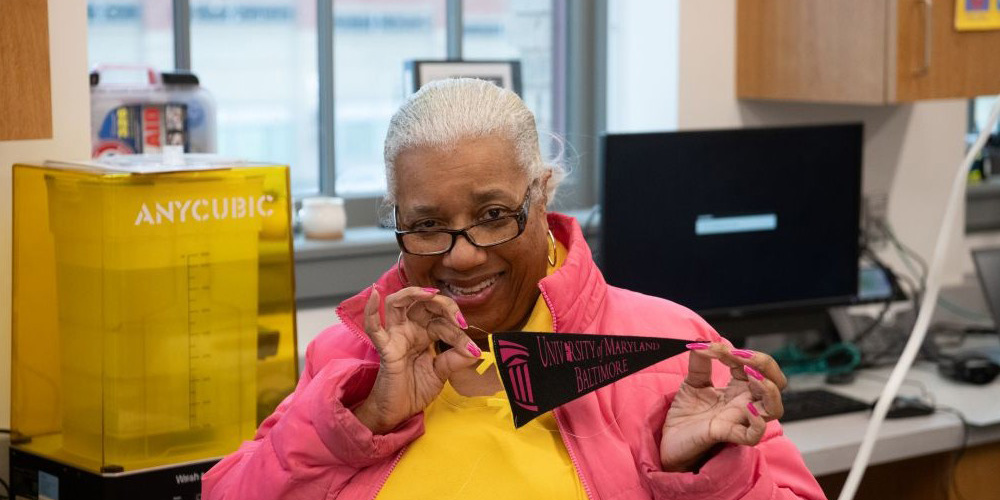 Community member Sandy Price holds a banner made at a recent class hosted through UMB’s collaboration with Open Works