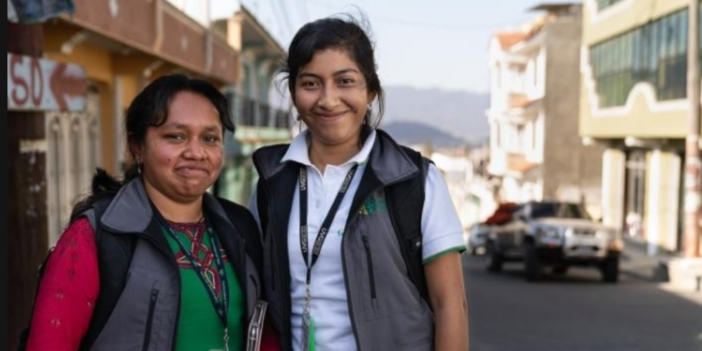 Two women pose for a photo in a street