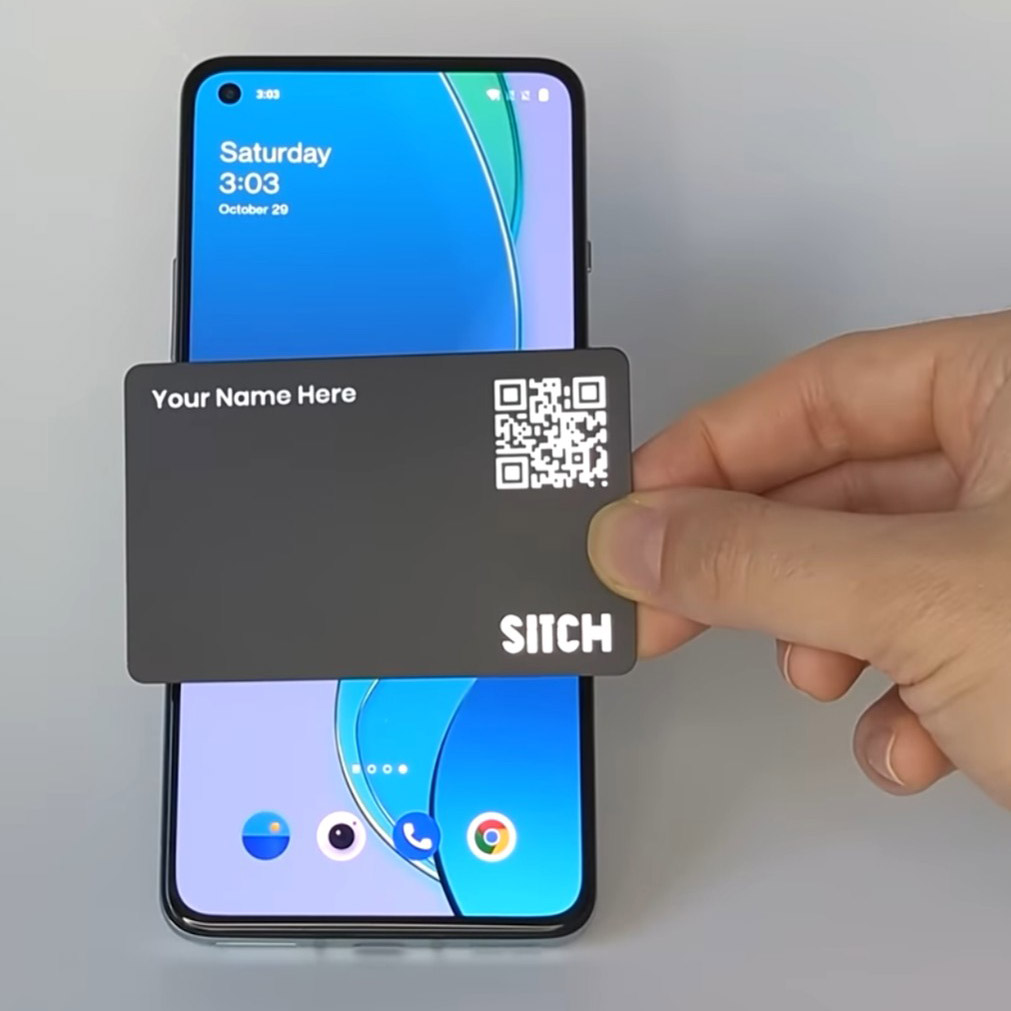 hand holds a credit card-like card near a mobile phone screen