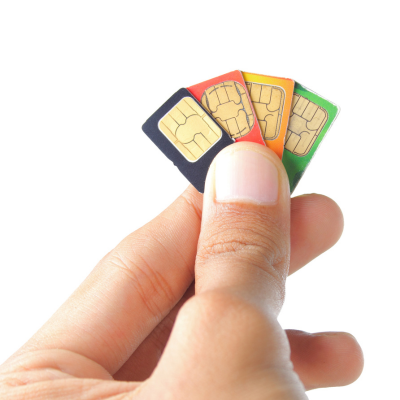 A hand holds four SIM cards.