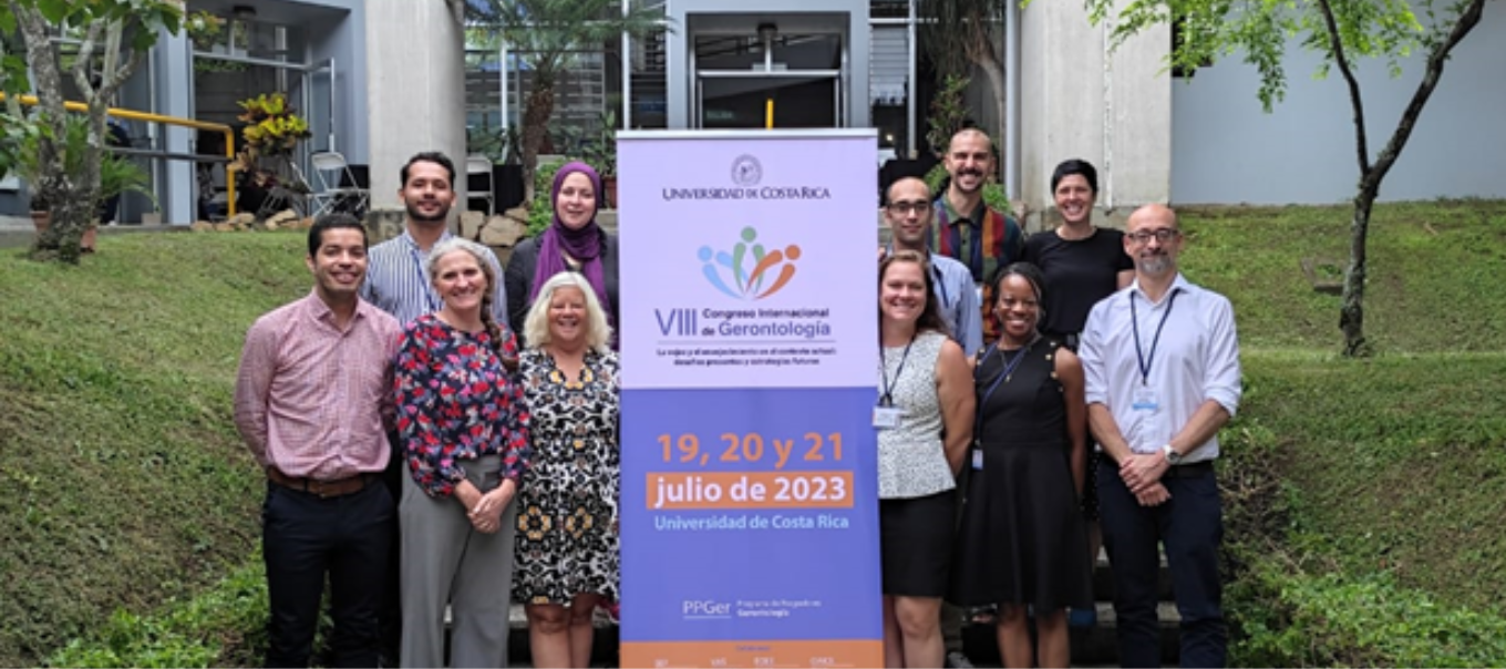 A group of people stand outside in Costa Rica around a conference banner