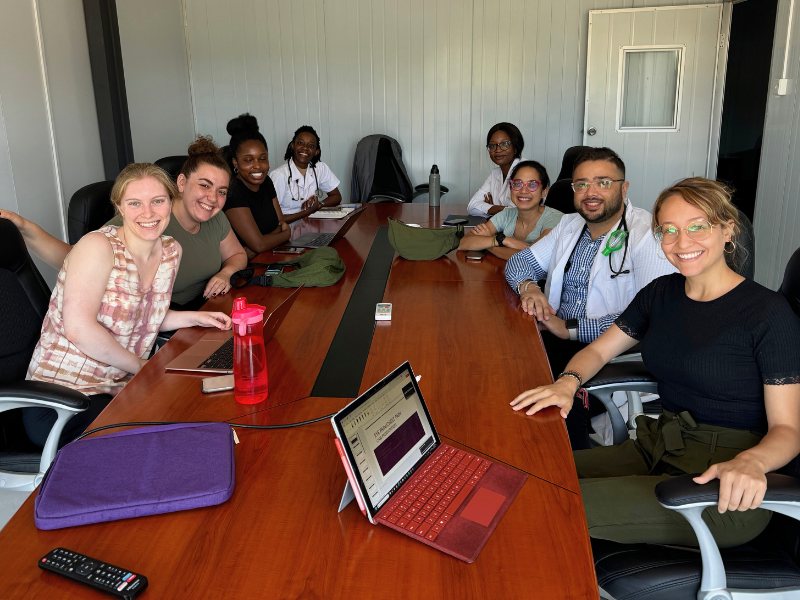 Students gather around a table with laptops
