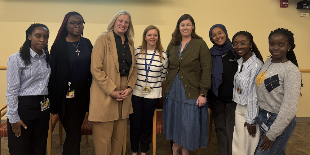 Speakers and students pose for a photo at the front of a classroom.