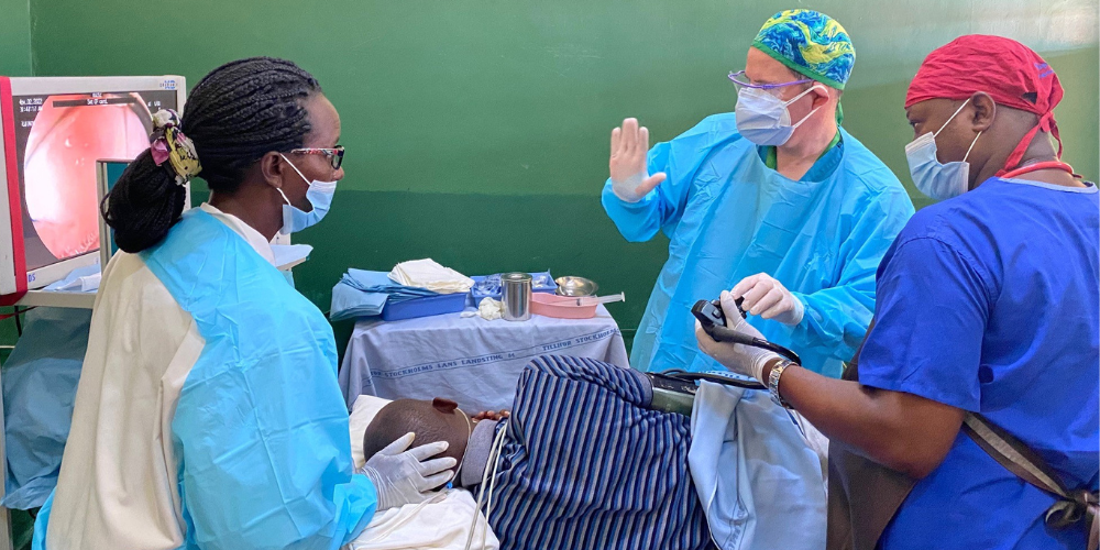 Three medical professionals conduct a procedure on a man