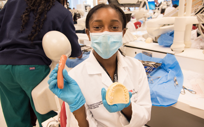 Najah Johnson holds up the products of her activities in the simulation lab at the School of Dentistry's Oral Health Promotion Program.