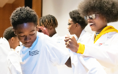 Sixth-graders who have been selected as UMB CURE Scholars received their white coats in a ceremony on Oct. 5  