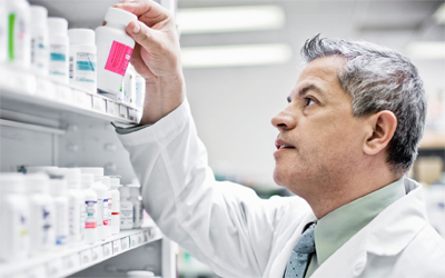 Tech in white coat holds pill bottle