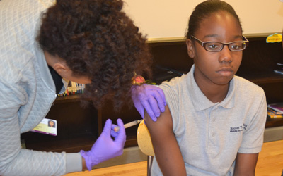 Seventh-grade student Latia Hale is immunized at a clinic held by Promise Heights at Booker T. Washington Middle School for the Arts