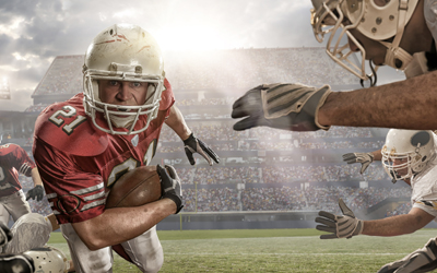 Running back with ball runs toward camera, about to be tackled 