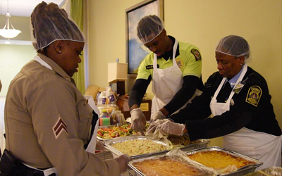 Cpl. Hazel Lewis (left) and Pfc. Ronald Nicholson (center), of the UMB Police Force, along with UMB security guard Evelyn Greenhill prepare to serve dinner to the guests at the American Cancer Society's Hope Lodge of Baltimore.