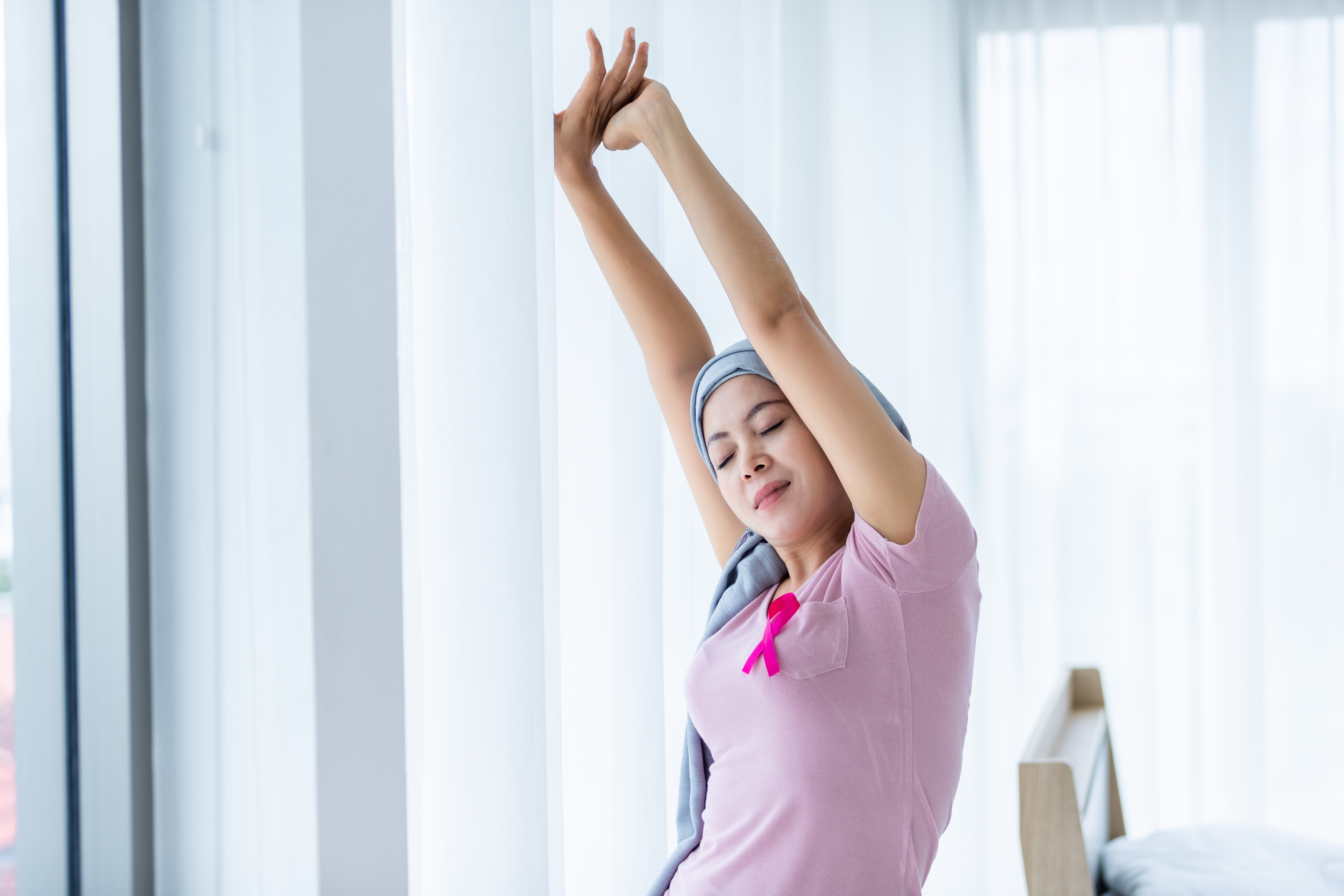 A woman who is undergoing cancer treatment stretching and exercising