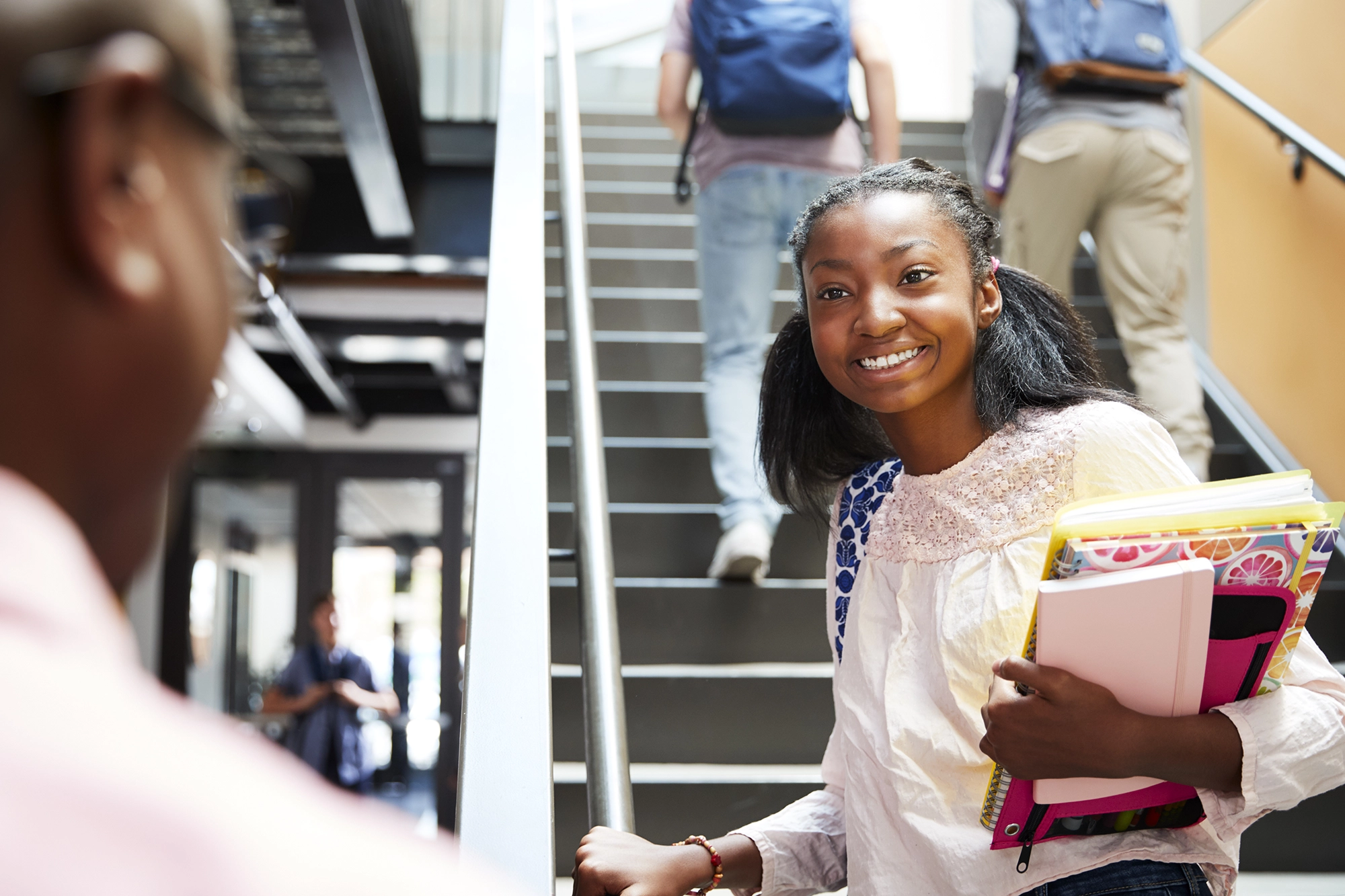 A young student talking to their teacher in a school hallway.
